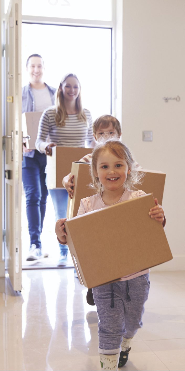 Family Carrying Boxes Into New Home On Moving Day