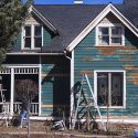 house with wood siding and chipped paint being repainted