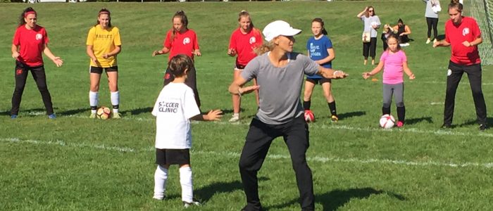 Olympic Gold Medalist Kristine Lilly teaches children on the soccer field.