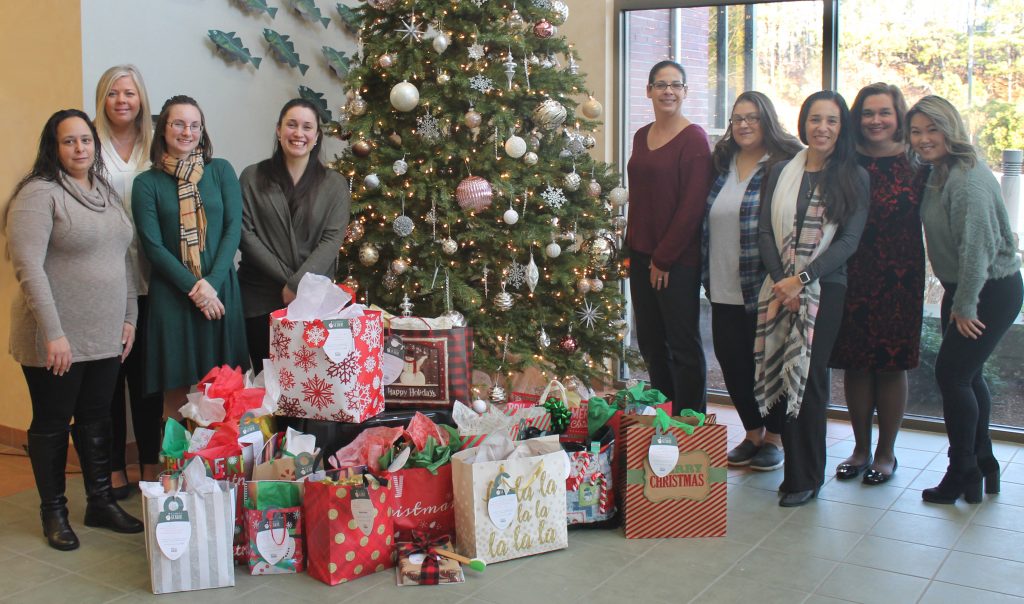 Coop employees gathered around decorated Christmas Tree surrounded by wrapped gifts for seniors in our community.