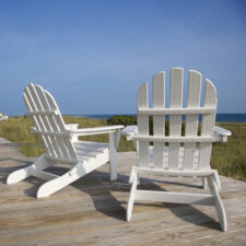 two white Adirondack chairs on dock of waterfront property