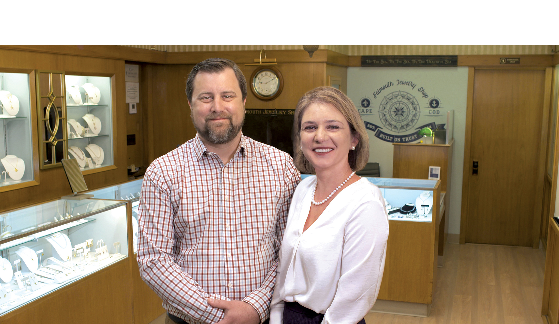 Stephen and Neda Sullivan, owners of Falmouth Jewelry, stand inside their shop with jewelry cases in the background