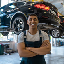 Car mechanic stands in front of vehicle on shop lift