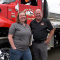 Abigail Our Rose and Chris Our stand in front of a red Robert B. Our Co. truck.