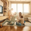 Family playing in sun-lit living room.